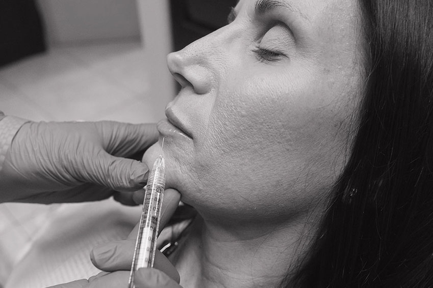 The image shows a person with a leaf covering their face, making a peace sign gesture with one hand, while the other hand is holding a large green leaf close to the camera.