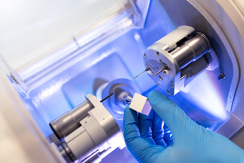 Hand examining precision equipment inside an industrial machine.