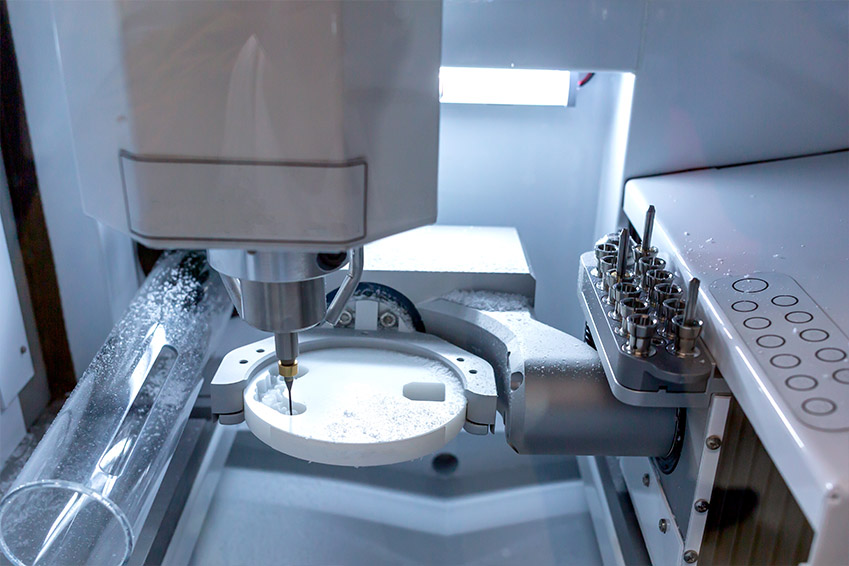 An industrial machine with a robotic arm, featuring a glass enclosure, where a white substance appears to be being processed.