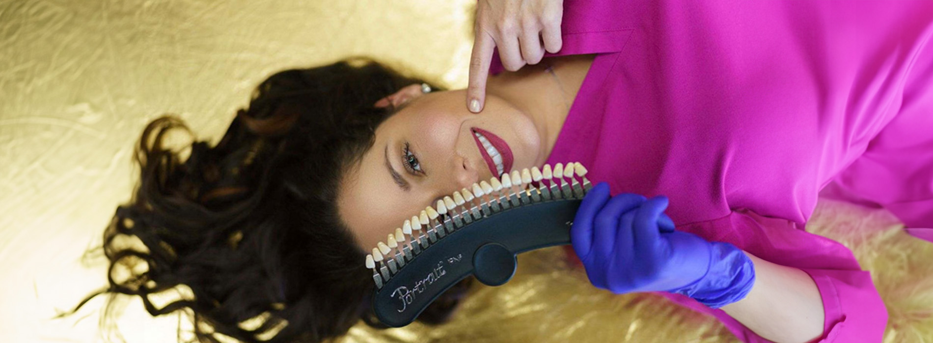 A woman with long hair, wearing a pink top, holding a green bottle near her face while lying on her back with one hand under her head.